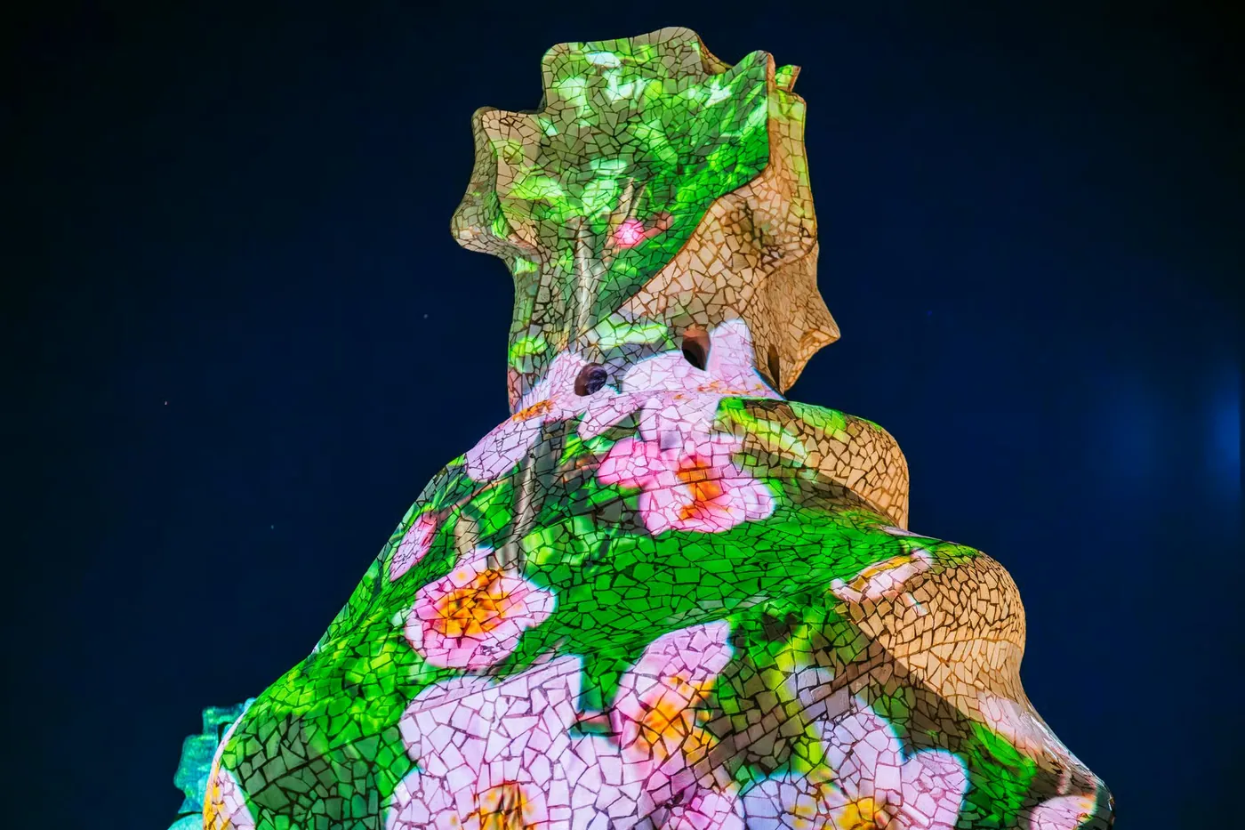 A rooftop chimney is covered in colorful projections during the night experience.